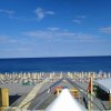Spiaggia con lettini e ombrelloni sotto un cielo azzurro.