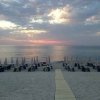 Spiaggia al tramonto con ombrelloni e cielo nuvoloso.