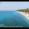 Spiaggia con mare azzurro e scogliera verde.