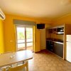 Cucina con pareti gialle, tavolo, sedie, frigorifero e fornello.
