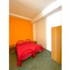 Camera da letto con pareti arancioni, letto matrimoniale rosso e armadio a destra.