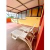 Terrazza coperta con due lettini bianchi e pavimento rosso.