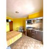 Camera con letto matrimoniale, cucina compatta e pareti gialle.