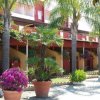Un complesso residenziale con palme e vasi di fiori colorati lungo un viale soleggiato.