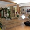 Una hall con pavimento piastrellato, piante e un banco reception decorato con specchi.