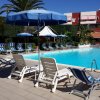 Lettini e ombrelloni blu e bianchi attorno a una piscina con cielo sereno.