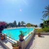 Piscina luminosa con fiori, piante e ampio cielo blu sullo sfondo.