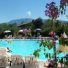 Piscina con lettini, fiori e montagne sullo sfondo.