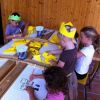 Bambini che fanno artigianato con carta gialla e pastelli.
