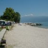 Spiaggia di ghiaia con tende da campeggio vicine e vista su un lago.