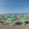 Spiaggia con ombrelloni verdi e gialli allineati sulla sabbia sotto un cielo sereno.