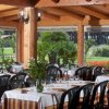 Sala ristorante con tavoli apparecchiati sotto una tettoia in legno, vista su giardino.