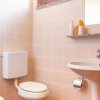 Un bagno con sanitari bianchi, lavandino e specchio su piastrelle beige.