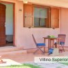 Esterno di un villino con veranda, tavolo, sedie e porta aperta.