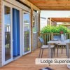 Terrazza in legno con tavolo e sedie sotto un portico, vicino a porte vetrate.