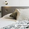 Letto matrimoniale con cuscini e coperta, lampada da lettura a parete.