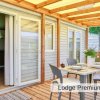 Veranda di legno con tavolo apparecchiato, porte scorrevoli bianche e sedie grigie.