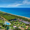 Vista aerea di un villaggio turistico sul mare, con piscine e giardini.