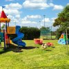 Parco giochi colorato su un prato, con scivoli e altalene.