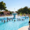 Persone fanno esercizi in acqua in piscina mentre due istruttori guidano.