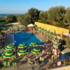 Piscina con ombrelloni verdi e gialli vicino al mare.