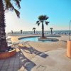 Area piscina con palme, lettini bianchi e vista sul mare al tramonto.