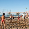 Persone giocano a beach volley su una spiaggia soleggiata.