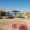 Area giochi sulla spiaggia, con scivoli e ombrelloni di paglia.
