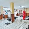 Palestra con attrezzi, pesi e un sacco da boxe rosso.