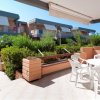 Terrazza con tavolo e sedie di plastica, circondata da folti cespugli.