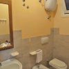 Bagno con lavandino, bidet e wc. Pareti gialle e piastrelle beige. Specchio sopra il lavandino.
