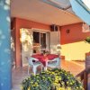 Veranda con tavolo, sedie e fiori colorati, parete arancione.