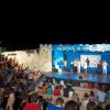 Spettacolo serale all'aperto con pubblico su gradinate.