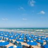 Spiaggia con file di ombrelloni blu.