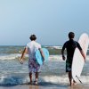 Due persone con tavole da surf si dirigono verso il mare.