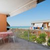 Balcone con tavolo rotondo, sedie bianche e vista sul mare.