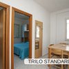 Tavolo con sedie vicino a due porte aperte, una con letto visibile.
