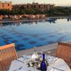Tavolo all'aperto con bicchieri e bottiglia di vetro vicino a una piscina riflettente.