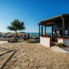 Passerella in pietra vicino alla spiaggia con ombrelloni gialli e bar in legno.