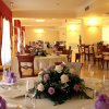 Sala da pranzo elegante con tavoli rotondi apparecchiati decorati con fiori viola e bianchi.