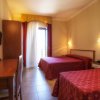 Camera d'hotel con due letti singoli, scrivania e porta finestra con tende.