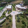 Viale con fontana, edifici moderni e giardini con palme.