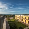 Edificio giallo con giardino verde e vista mare sotto un cielo sereno.