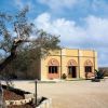 Edificio giallo ocra con tre archi e un albero in giardino.