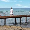Uomo su un pontile sopra l'acqua, altre persone nuotano.