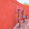 Persone che fanno la doccia su un muro rosso all'aperto.