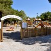 Ingresso a un parco giochi con staccionata e cartelli.