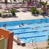 Piscina con corsie per nuoto, persone in acqua e lettini a bordo.