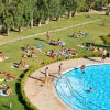 Persone prendono il sole su un prato vicino a una piscina.