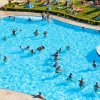 Persone nuotano nella piscina affollata.